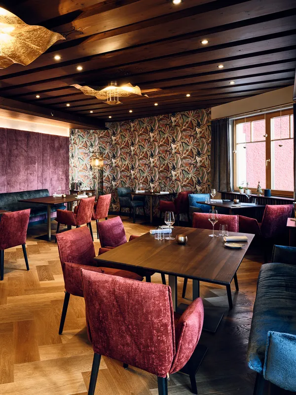 Modern restaurant interior with velvet chairs, wooden tables, and vibrant wall decor